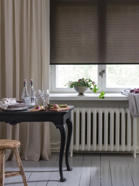 Ett svart bord uppdukat med mat framför ett fönster med en mörkgrå rullgardin