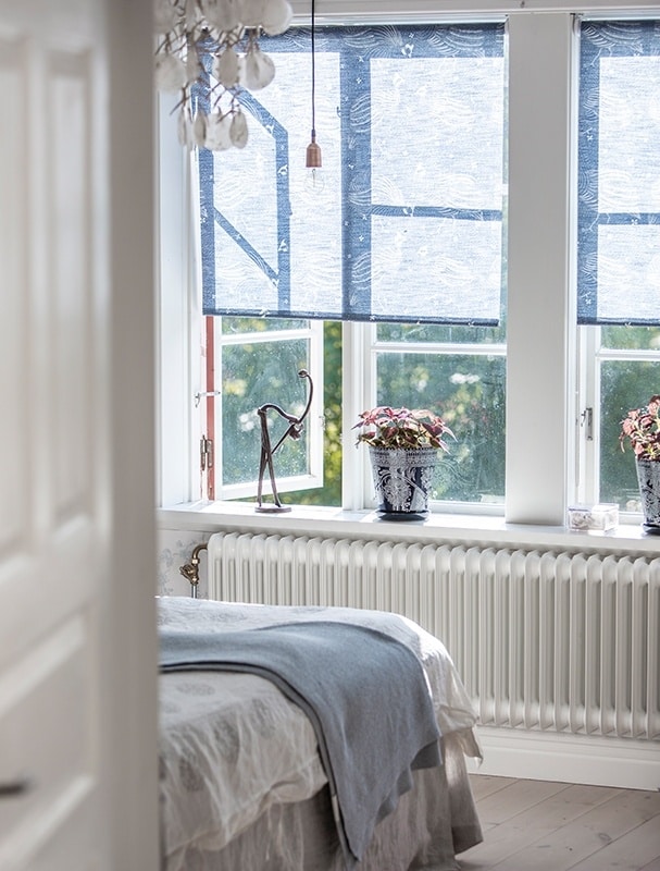 Ett ljust inrett sovrum med blå rullgardiner
